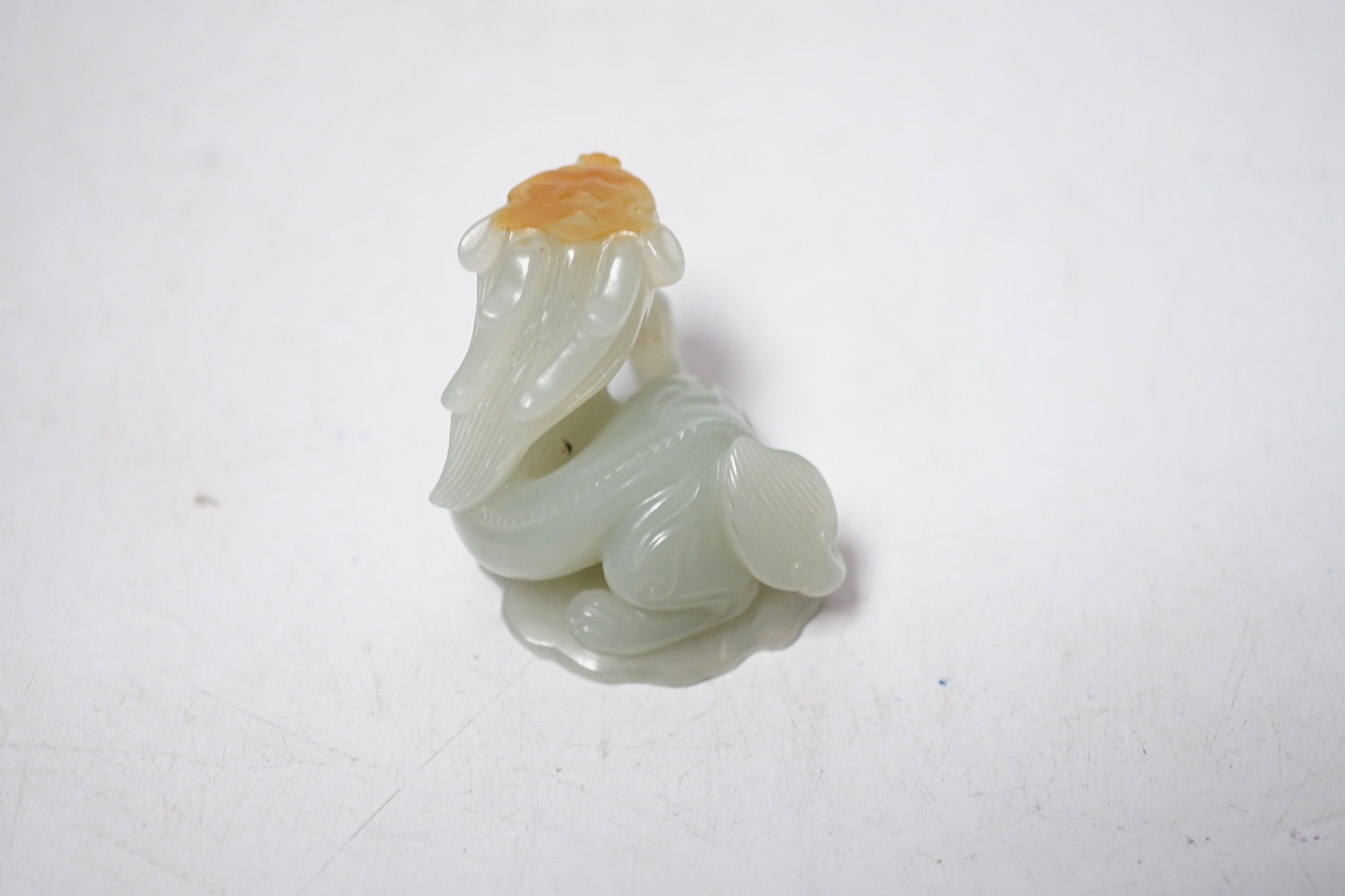 A Chinese pale celadon and russet skin jade figure of a dragon, 4cm high